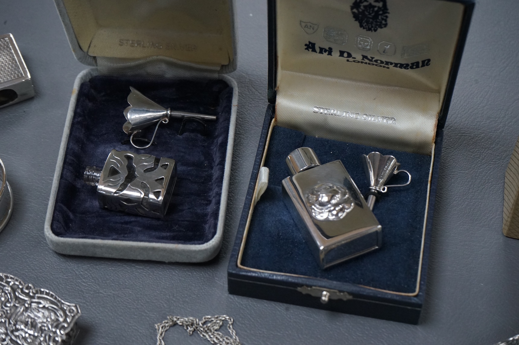 A group of mainly modern silver collectables including three assorted scent flasks and funnels by Ari D. Norman, two money clips, matchbox sleeve, napkin ring, pill box, three pendants including ingot and a pair of Victo